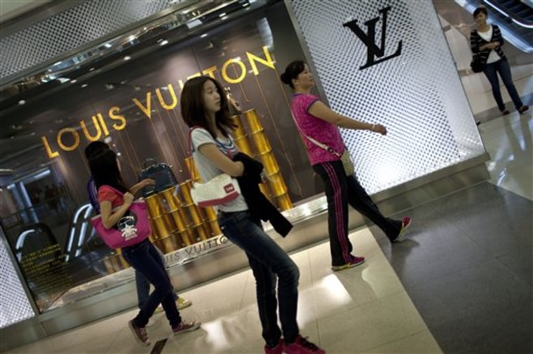 In this photo taken Thursday, Sept. 23, 2010, women walk past a Louis Vuitton store at a luxury shopping center in downtown Beijing. China, now the world's second largest economy, spent tens of billions of dollars on a dazzling Beijing Olympics in 2008 and has sent astronauts into space. Yet it also remains a major recipient of foreign aid, a fact that a growing number of taxpayers and lawmakers in donor countries are questioning. (AP Photo/Alexander F. Yuan)